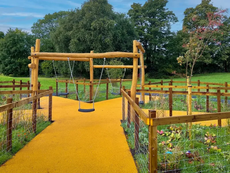 Branching Corkeen pathway under a timber swing structure in a country garden