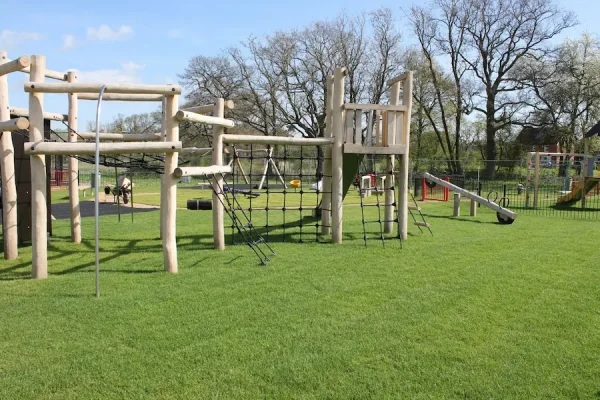 EcoSmart installed under play equipment with grass grown through, creating a natural, camouflaged look