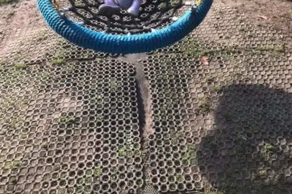 Worn down and separating rubber grass mats underneath nest swing