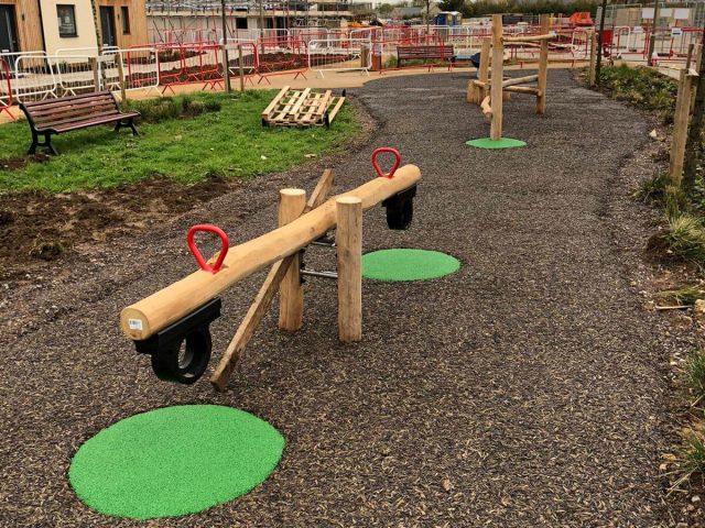 Green EPDM wear pads under playground equipment in JungleMulch residential playground