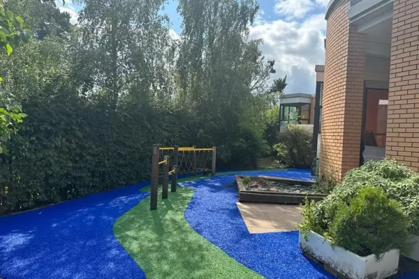 Vibrant blue and green EPDM pattern in narrow play area outside Studley school