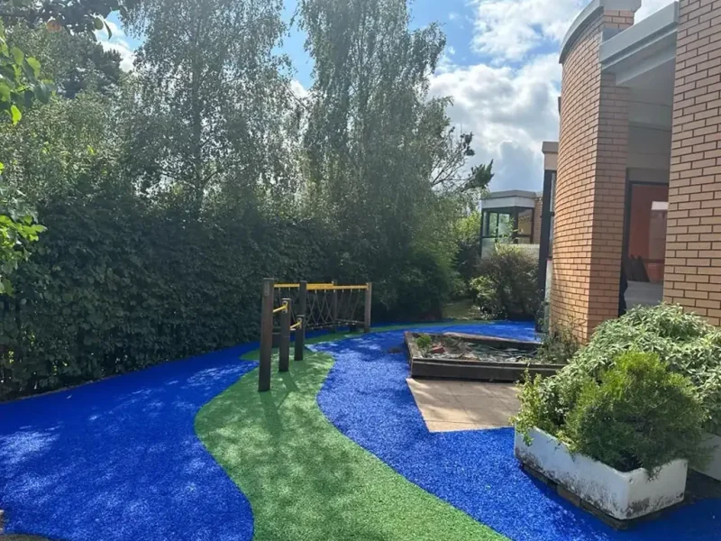 Vibrant blue and green EPDM pattern in narrow play area outside Studley school