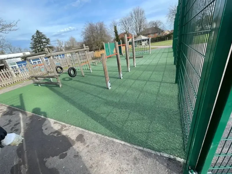 Large area of green EPDM below fenced play area