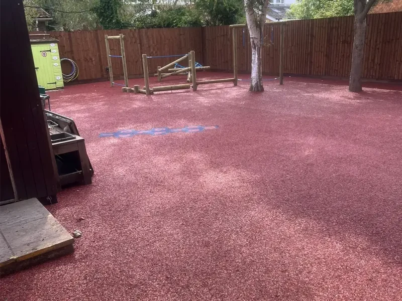 Large red EPDM Mulch play area with trim trail and trees seamlessly installed around