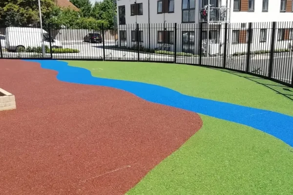 green, brown, and blue rubber surfacing in a river bank design on playground made with rubber wetpour materials