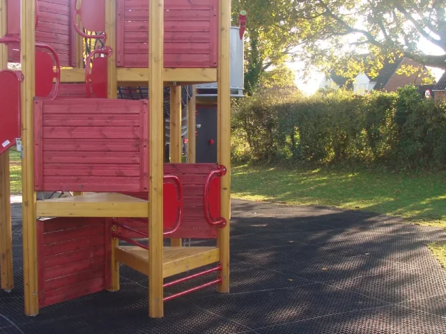 FireSmart Grass mats installed under a red play tower