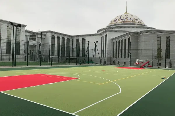 Lime green FlexCourt basketball court with red shooting zone outside classical architecture