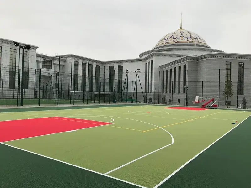 Lime green FlexCourt basketball court with red shooting zone outside classical architecture