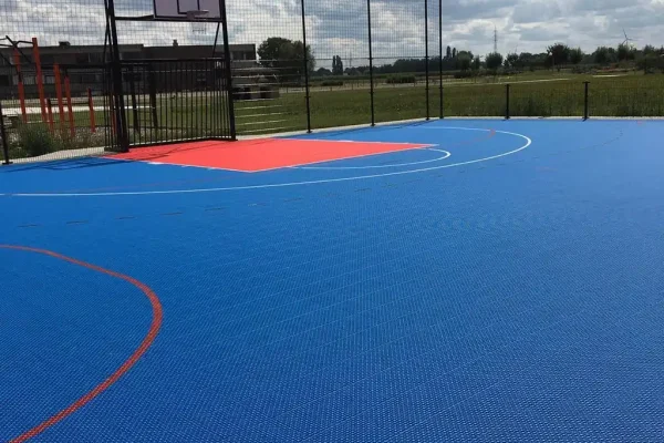 A blue FlexCourt multi use games area with red scoring zone for basketball