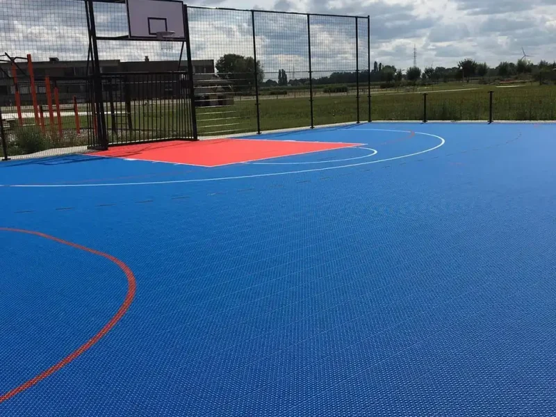 A blue FlexCourt multi use games area with red scoring zone for basketball