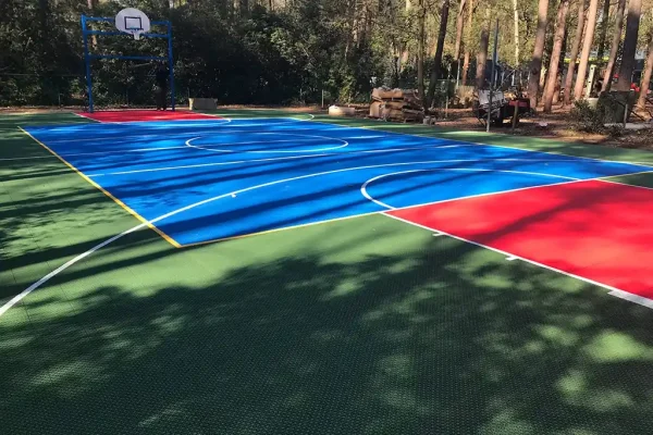Blue FlexCourt basketball court in a wooded area with red scoring zones