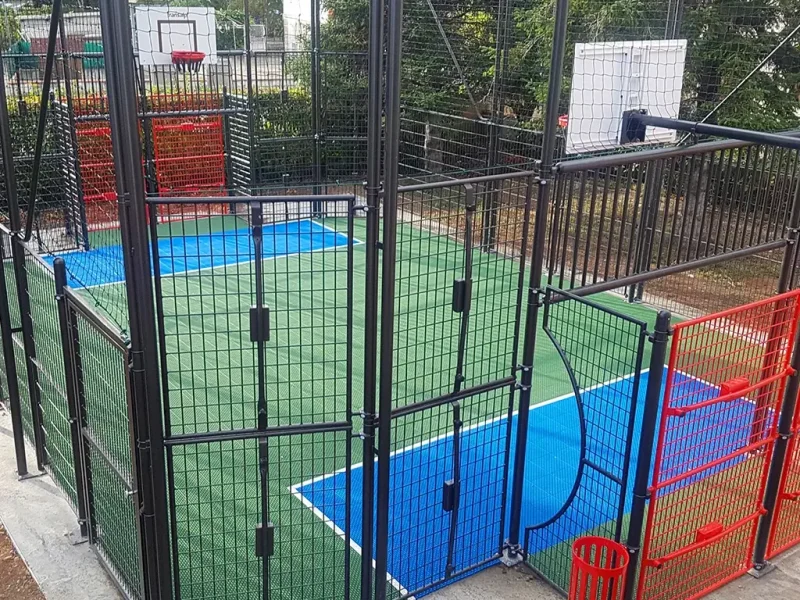 An enclosed mini multi use games area with green FlexCourt and blue scoring areas for football