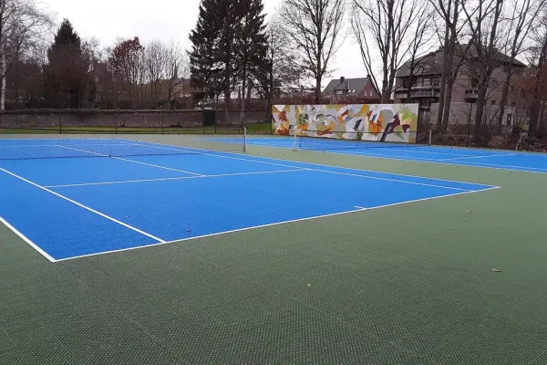 Two blue FlexCourt tennis courts with abstract mural in background