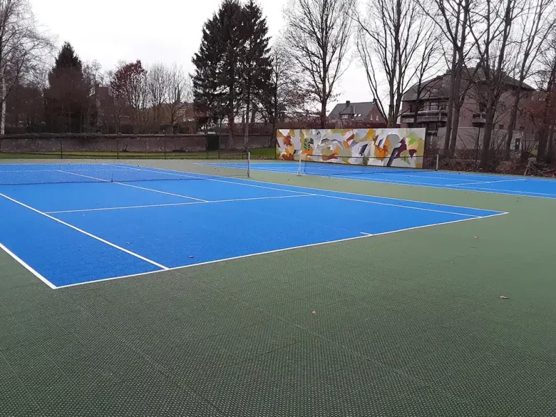 Two blue FlexCourt tennis courts with abstract mural in background
