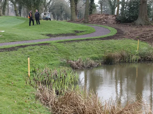 Red rubber mulch pathway in golf course next to water hazard