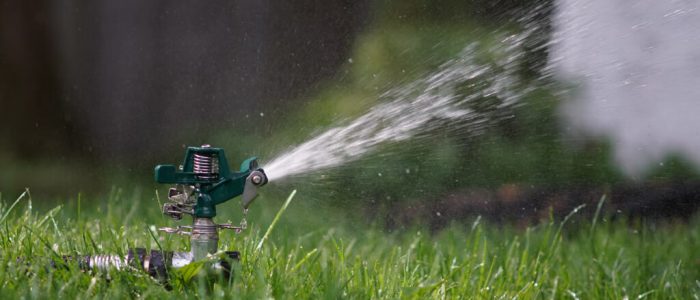 green and black sprinkler on green grass during daytime