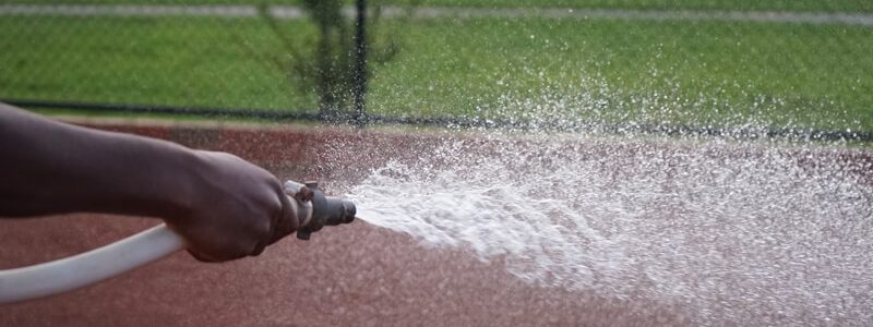 person hosing sports track