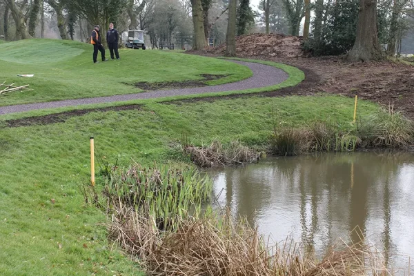 Red rubber mulch pathway in golf course next to water hazard