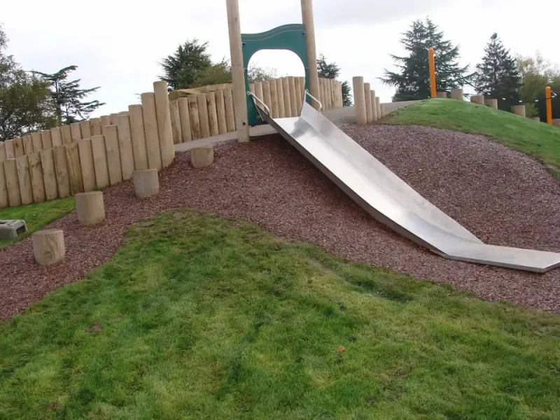 Original JungleMulch installed on a steep slope with stepping stoens and a slide in a park play area