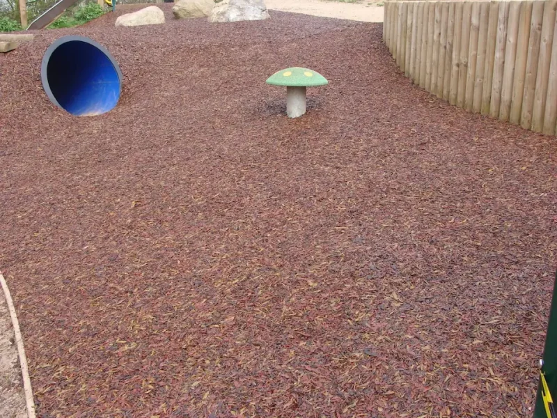 Original JungleMulch installed on a sculpted terrain with decorative toadstool and play tunnel in a park