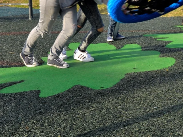 Children running on rubber mulch surfacing with green EPDM leaf designs