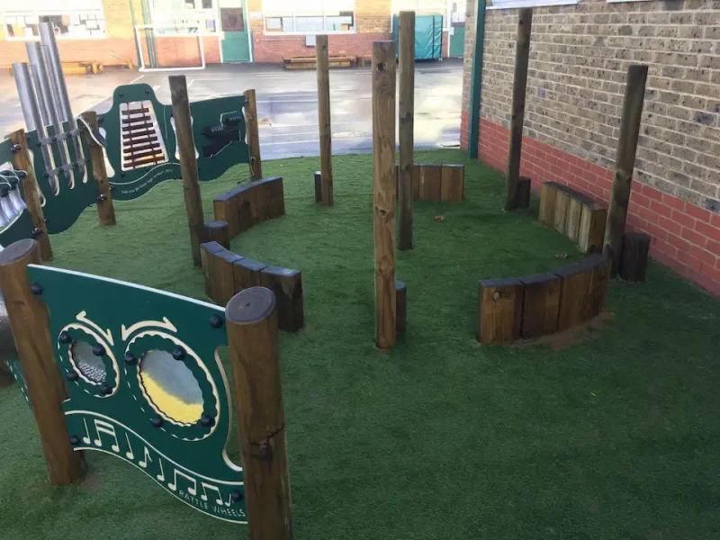 Shaded area of playground with LushLawn underneath seating circle and musical play panels