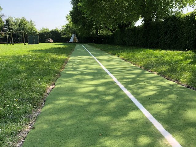 Green artificial grass running track in field