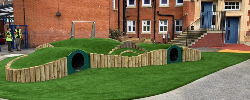 Green Frog Artificial Grass installed for a school over play tunnel mounds
