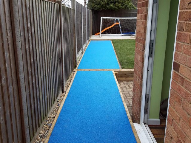 Blue wetpour surfacing along the side of a building in a school