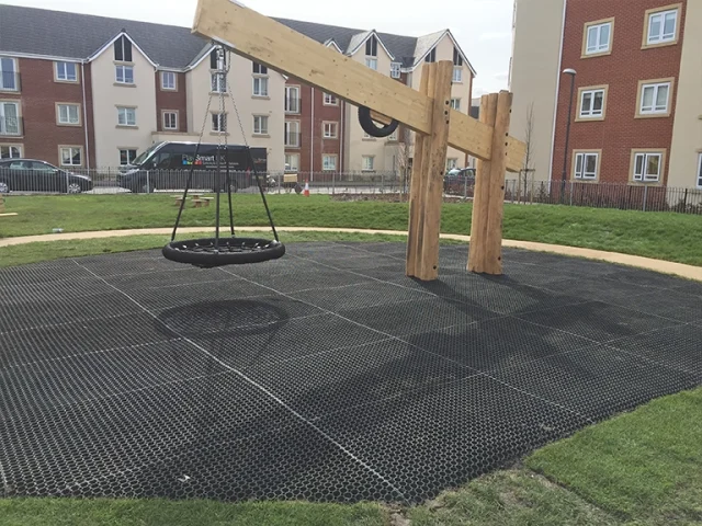 Grass mats in residential playground underneath giant nest swing