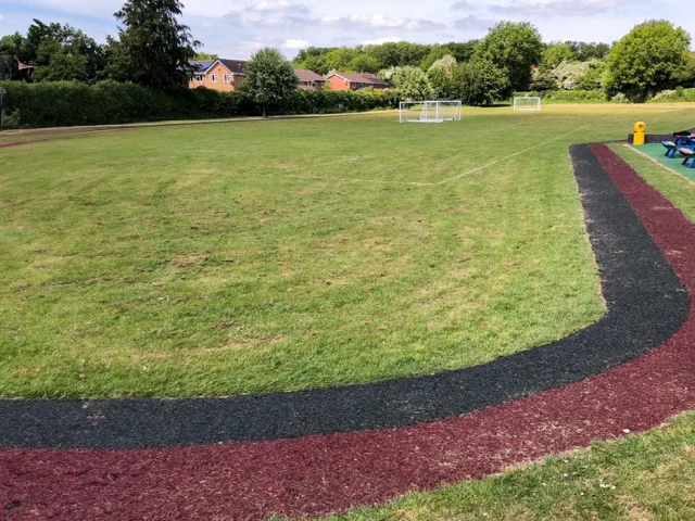 Red and Black Rubber Mulch running track around grass field