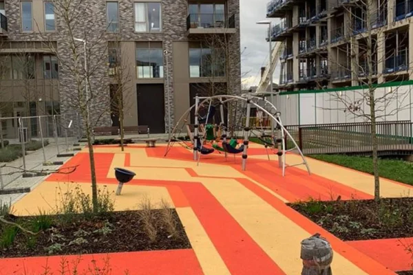 Wetpour surface design in public park space. Vibrant red and yellow criss-cross design creating a modern, attractive central attraction for the local area