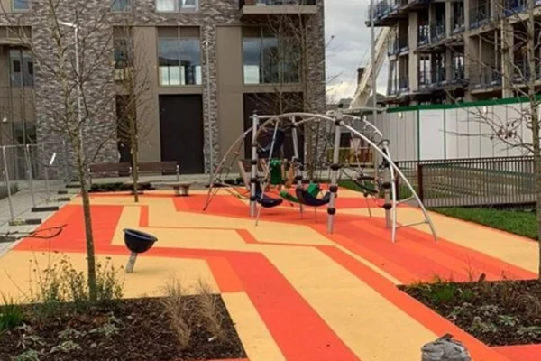Wetpour surface design in public park space. Vibrant red and yellow criss-cross design creating a modern, attractive central attraction for the local area