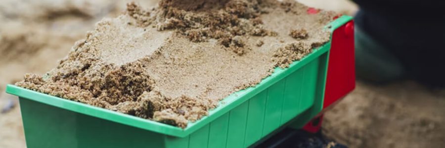 Child playing with sand and a toy digger