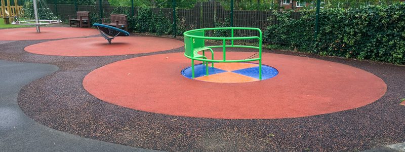 SmartPave playground installation with red mixed rubber surfaces around wheelchair accessible roundabout