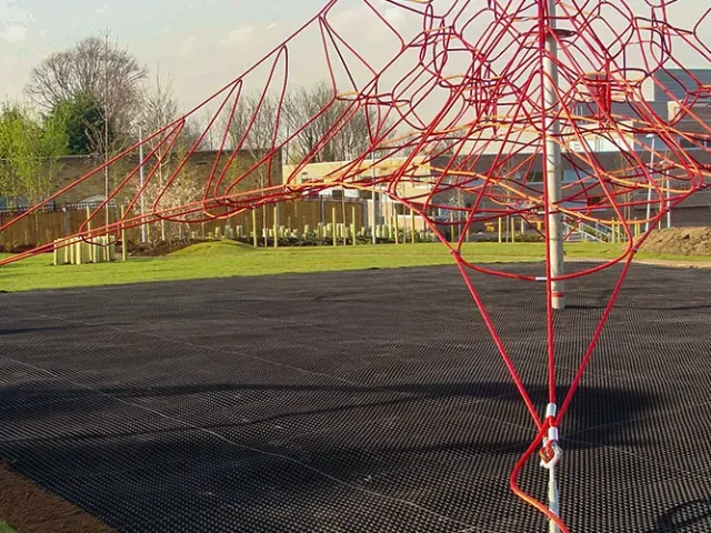 Rubber playground matting installed underneath a large red rope climbing frame
