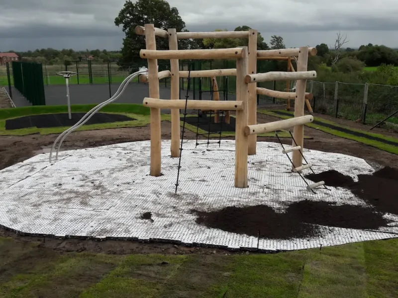 Mid-installation process of SmartPlay rubber mat with soil layer being applied